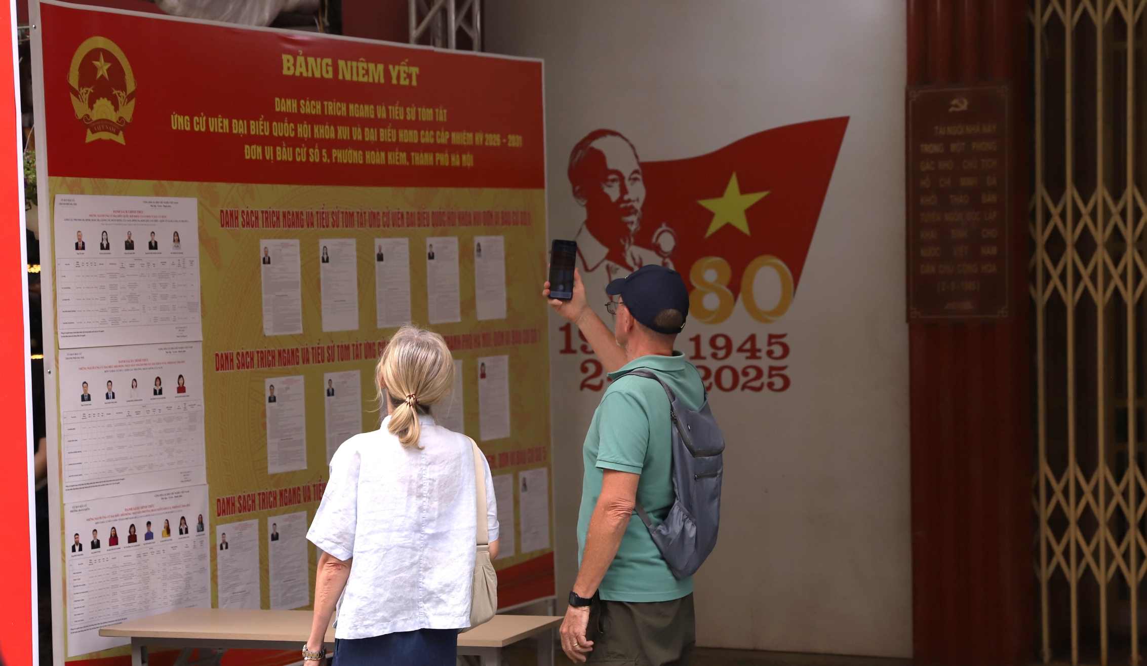 Du khách nước ngoài xem pano tuyên truyền về bầu cử. Ảnh: Minh Vũ
