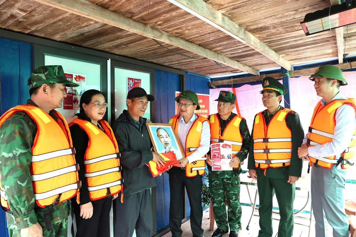 Mr. Cao Tuong Huy, Secretary of the Party Committee - Chairman of the People's Council of Van Don Special Zone - and the working delegation presented photos of Uncle Ho, national flags and election propaganda materials to fishermen. Photo: Van Don e-Portal