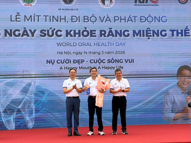 PGS Trần Cao Bính tặng hoa và kỉ niệm chương cho Thứ trưởng Trần Văn Thuấn tại sự kiện phát động Rằng Hàm Mặt thế giới. Ảnh: Đức Vân