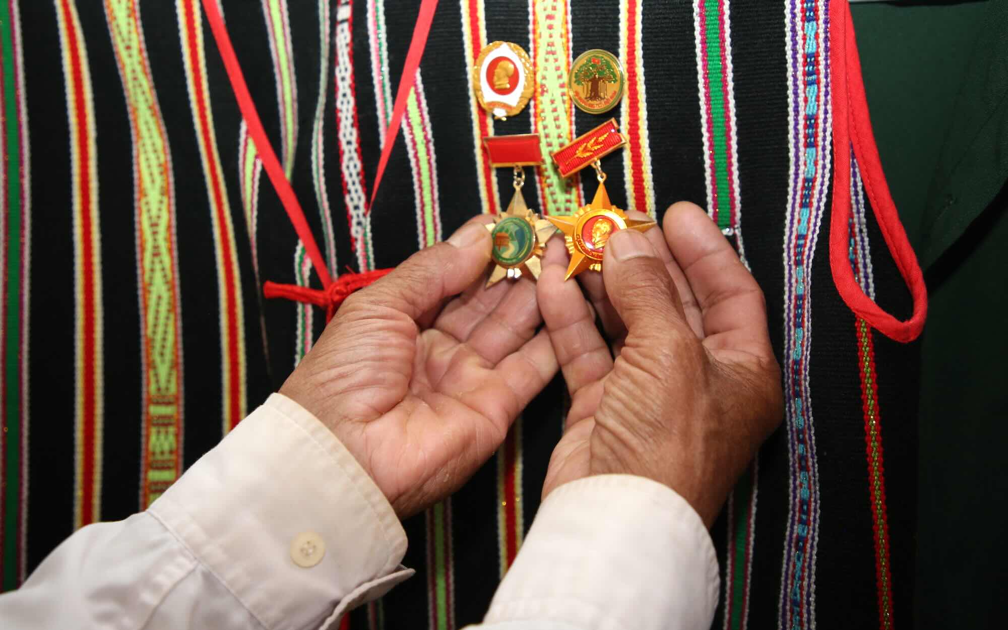 Trước giờ đến điểm bầu cử, già làng Điểu Sranh cẩn thận chỉnh lại trang phục và những tấm huân chương gắn trên áo. Ảnh: Sáng Tuấn