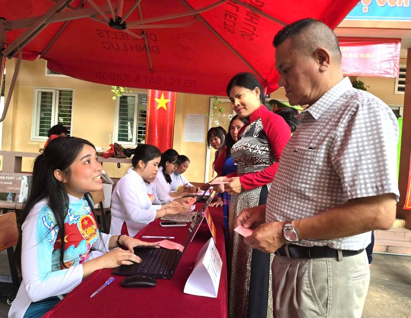 Nhân viên tổ bầu cử mặc áo dài có nội dung tuyên truyền về bầu cử đại biểu Quốc hội khóa XVI và HĐND các cấp. Ảnh: Nam Dương