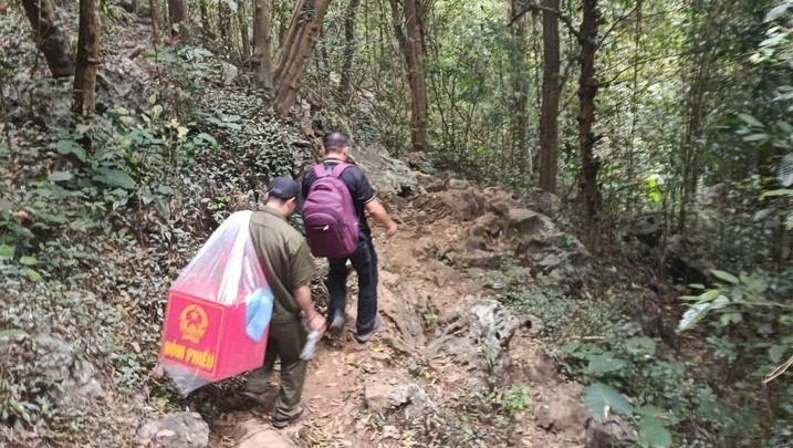 Extra ballot boxes are carried into Lan Dat hamlet, overcoming steep rocky outcrops. Photo: Huu Lien Commune