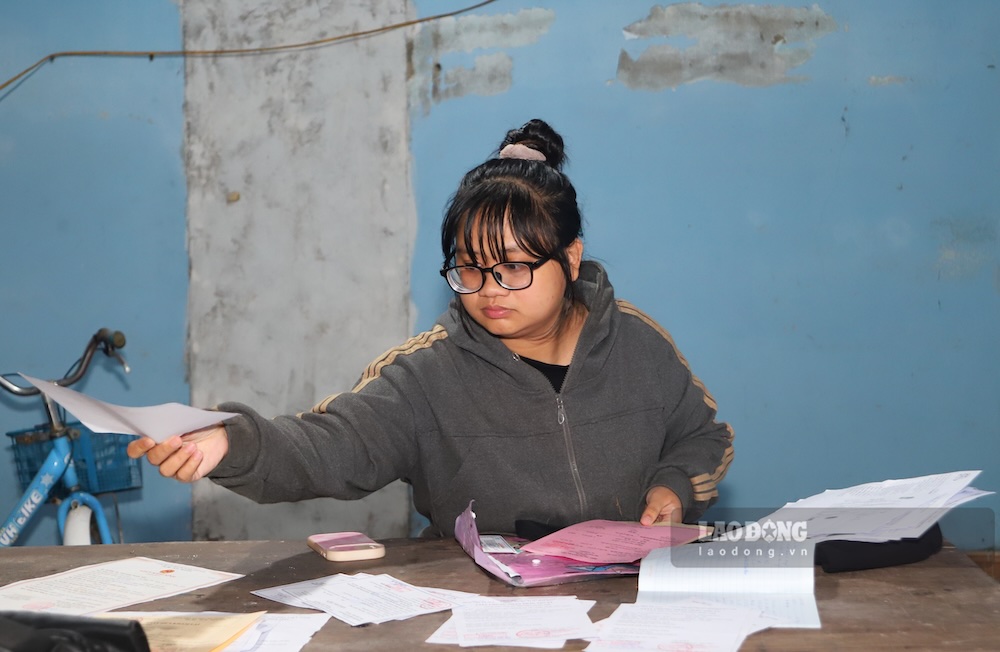 Chị Trần Tường Giang (mẹ bé Nhi) ngồi xem lại toàn bộ giấy tờ bệnh án của con để chuẩn bị đưa bé tiếp tục nhập viện. Ảnh: Nguyễn Luân