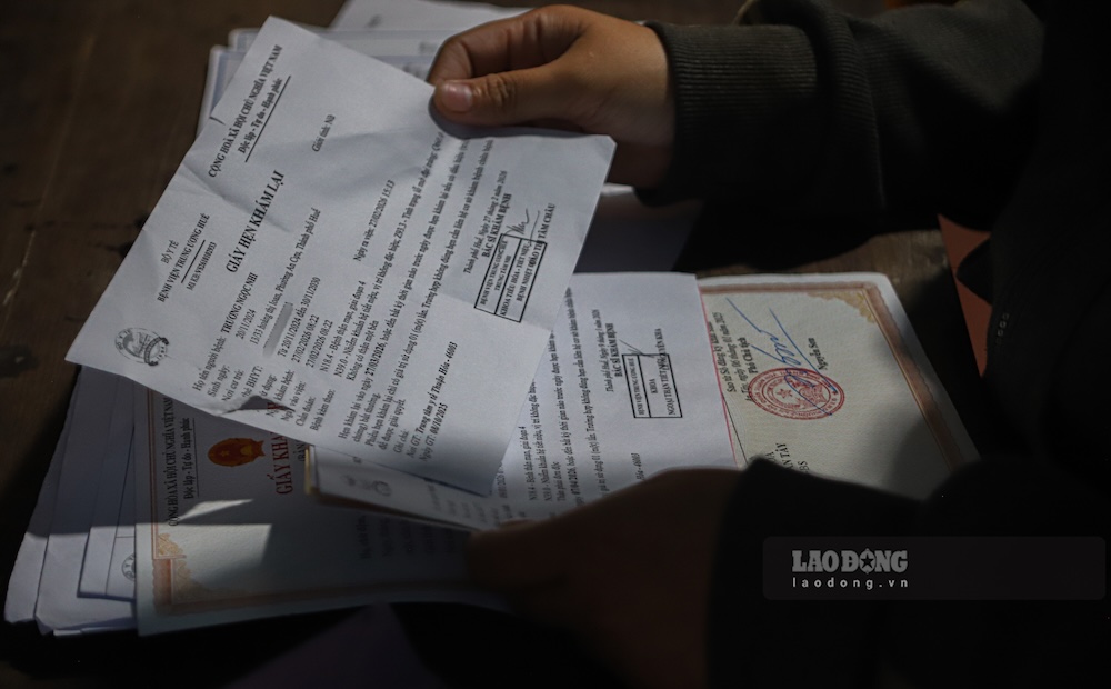 Người mẹ tuôn nước mắt khi nhìn vào giấy tái khám của con gái. Ảnh: Hồng Quân