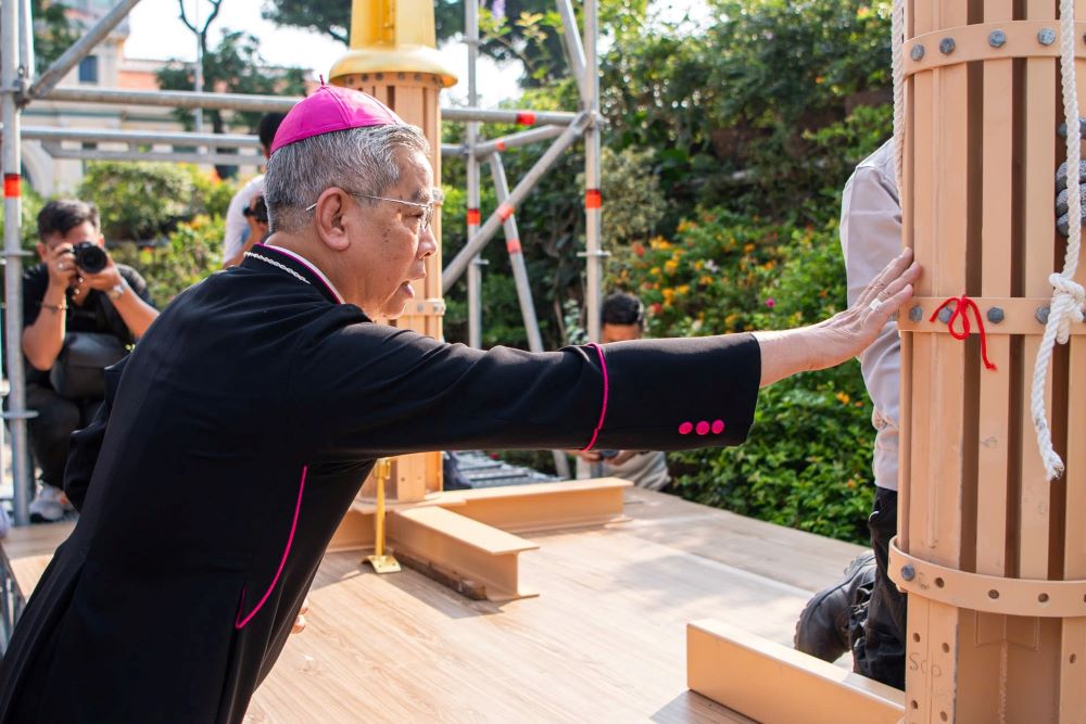 Đức Tổng Giám mục Giuse Nguyễn Năng chạm tay vào thánh giá trước khi đưa lên lắp đặt như một lời chúc lành, cầu mong quá trình vận chuyển được bình an. Ảnh: Anh Tú