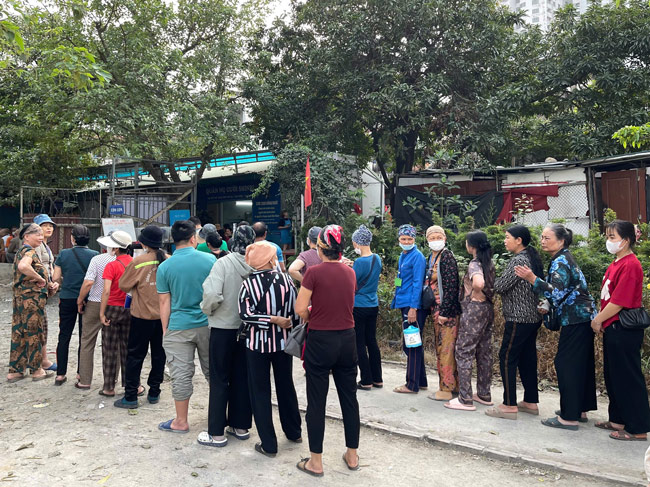 Nhiều bệnh nhân và người nhà xếp hàng chờ tới giờ mua cơm 2.000 đồng. Ảnh: Tạ Mai