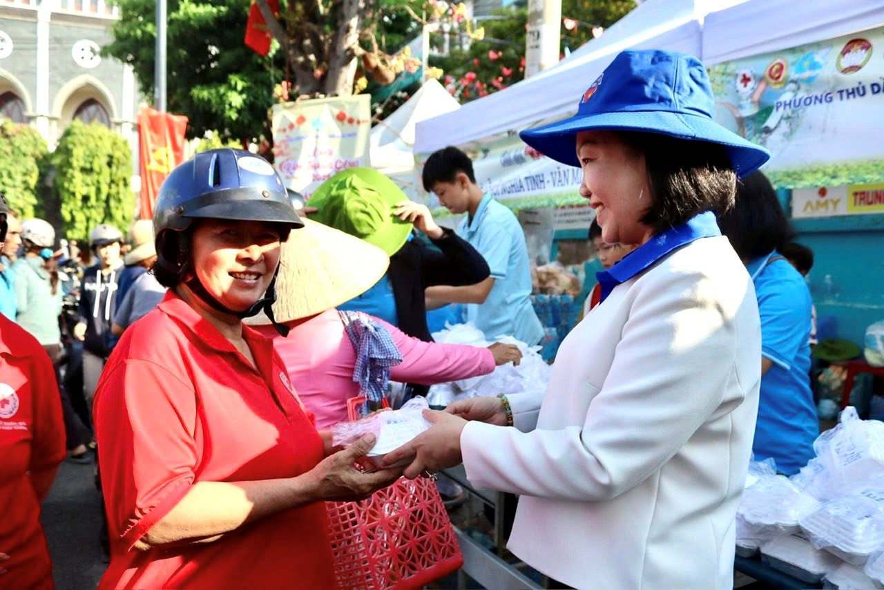 Mme Nguyễn Thu Cúc - Secrétaire du Comité du Parti, Présidente du Conseil populaire du quartier de Thủ Dầu Một distribue de la nourriture aux personnes allant au festival. Photo: Đình Trọng