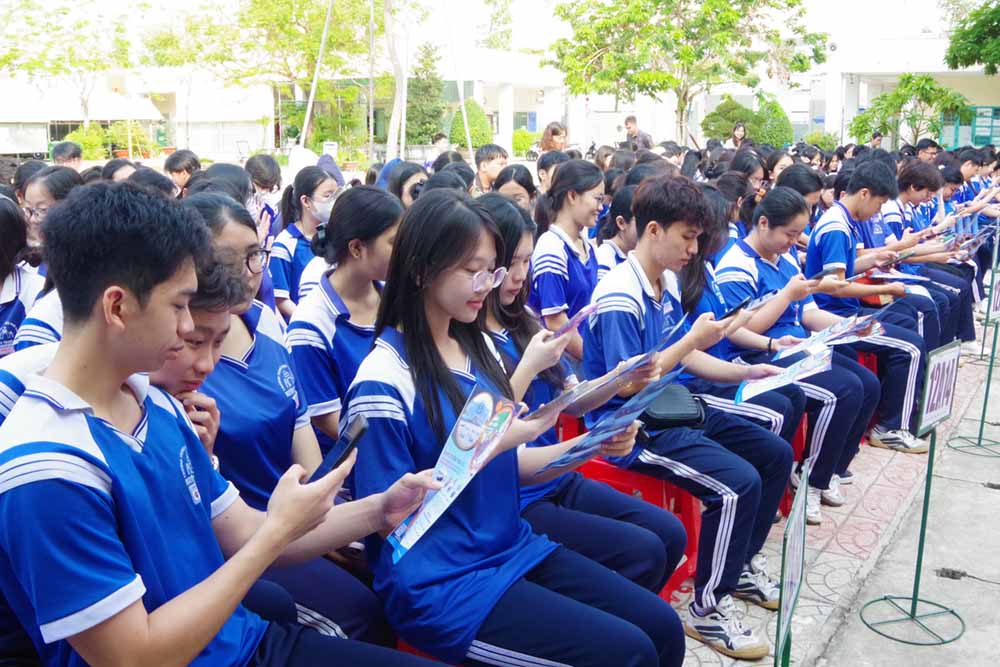 Các học sinh được hướng dẫn sử dụng điện thoại thông minh quét mã QR và truy cập các nền tàng số để tìm hiểu chi tiết về công tác tuyển sinh quân sự.