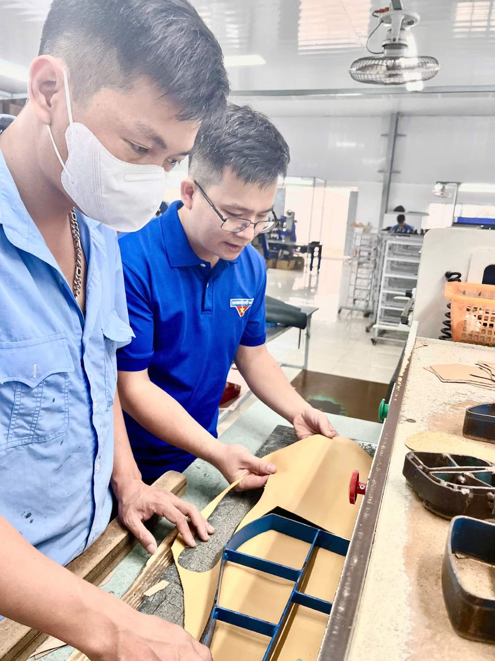 Anh Hậu (bên phải) kiểm tra công đoạn chặt da lót trong sản xuất giầy ủng da tại xí nghiệp. Ảnh: NVCC