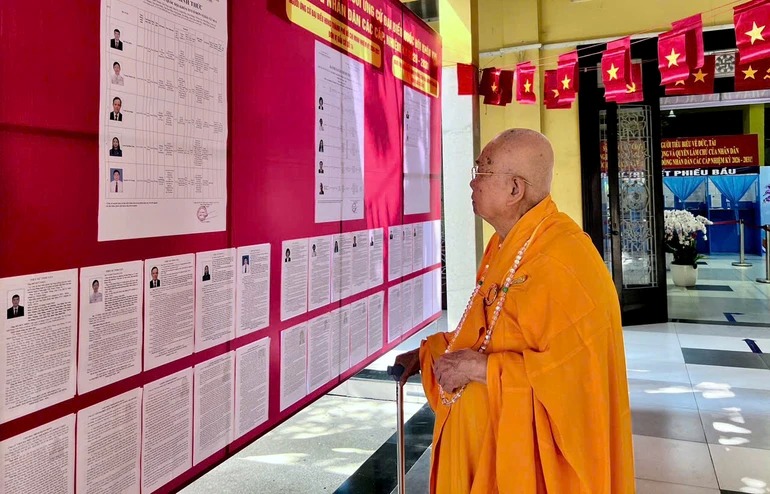 A monk is learning about information about candidates for the 16th National Assembly and People's Council Deputies at all levels for the 2026-2031 term listed at the Vinh Nghiem Pagoda polling station (Xuan Hoa ward, Ho Chi Minh City) - Photo: Quang Dao/BGNa