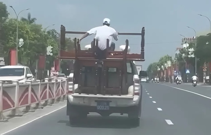 Driving a blue-plated pickup truck carrying tables, chairs and bulky people, the driver was fined. Photo: Cut from clip