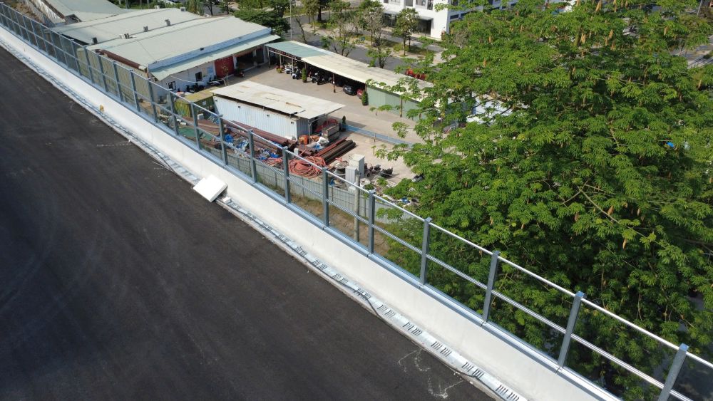 [Ảnh 4] Đoạn cầu cạn dài hàng km xuyên qua các tòa nhà cao tầng đã thảm nhựa xong, hiện công nhân đang tiến hành lắp đặt hệ thống lan can thép.