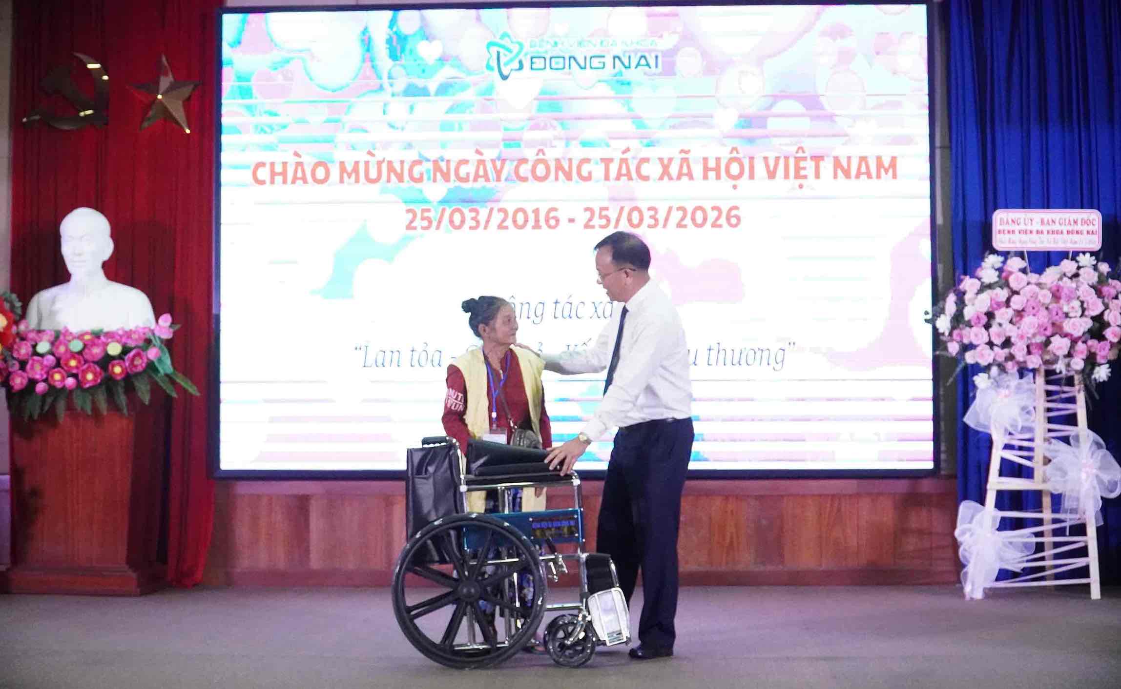 Giám đốc Bệnh viện Đa khoa Đồng Nai Ngô Đức Tuấn tặng xe lăn cho bệnh nhân thông qua thân nhân bệnh nhân. Ảnh: HAC