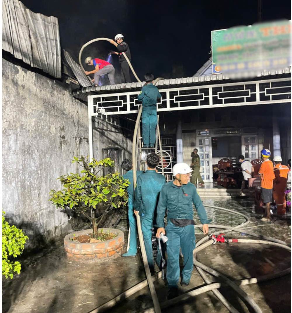 Lực lượng chức năng trèo lên mái nhà bên cạnh để kéo vòi nước chữa cháy qua. Ảnh: Lê Vy