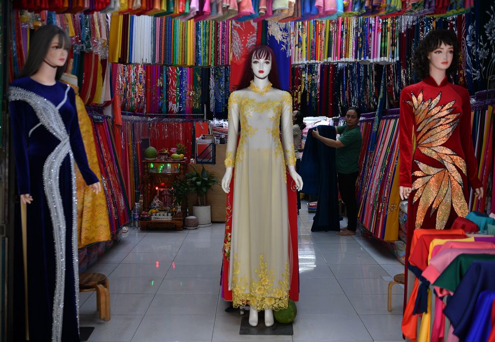 Không gian gian hàng áo dài với ma-nơ-canh mặc sẵn sản phẩm, nổi bật giữa hàng trăm loại vải, thu hút khách hàng lựa chọn và đặt may theo yêu cầu.  