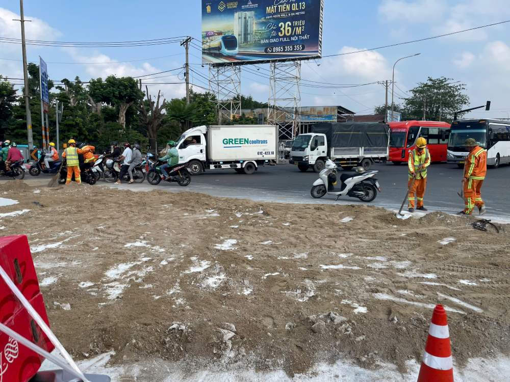 Các lực lượng đang tích cực dọn dẹp phần sơn bị đổ tràn ra đường. Ảnh: Anh Tú
