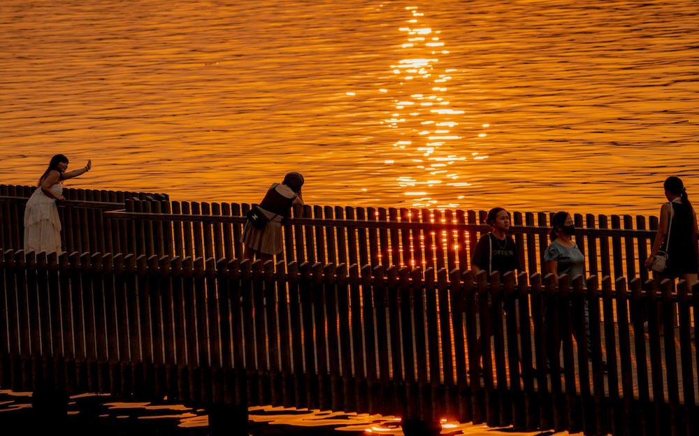 Hoàng hôn buông trên mặt nước, nhiều người dừng chân chụp ảnh, lưu giữ khoảnh khắc yên bình.