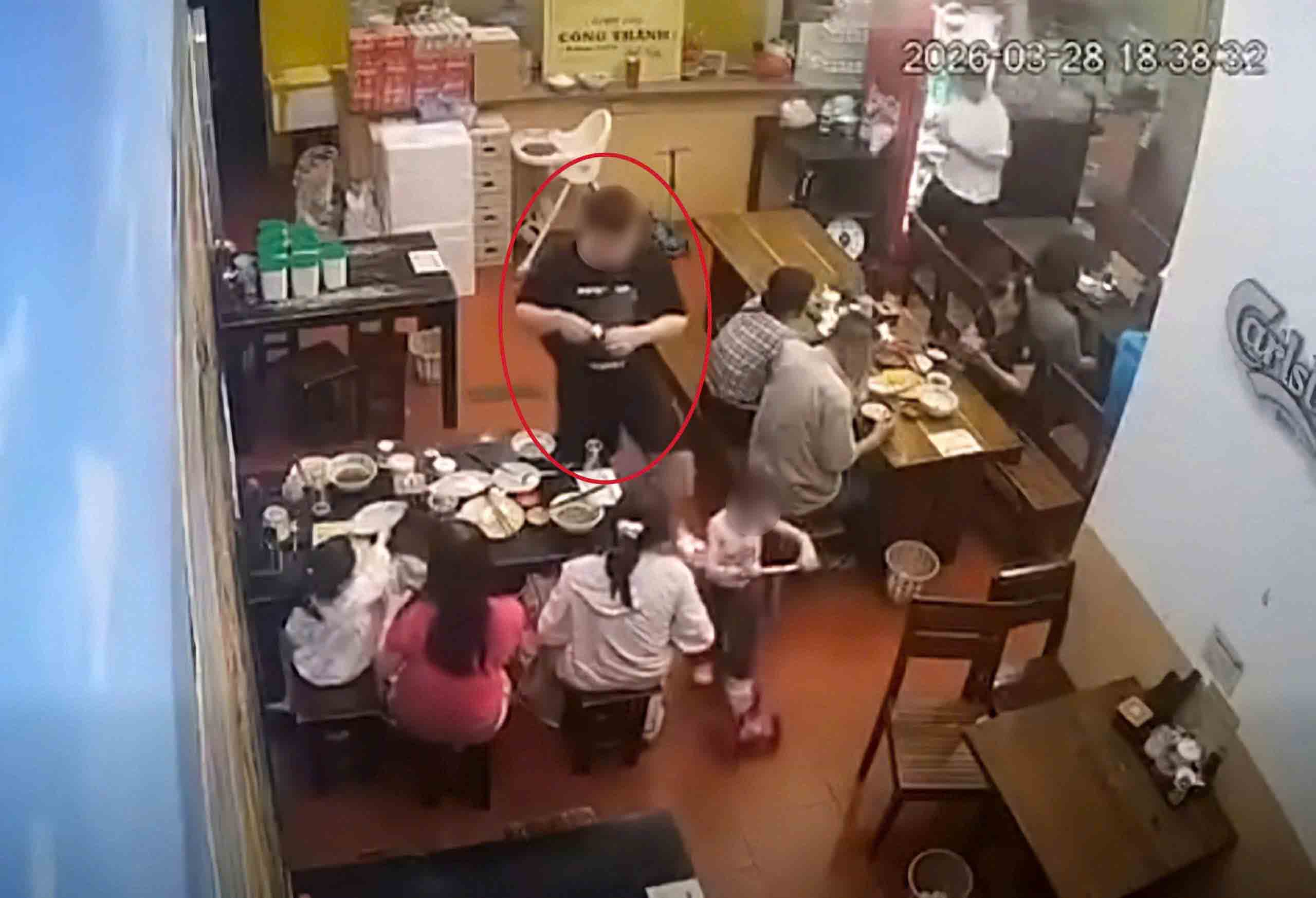 Nam thanh niên áo đen (khoanh đỏ) có hành vi dùng chân đạp vào cháu bé trong quán ăn ở Hà Nội. Ảnh: Cắt từ clip
