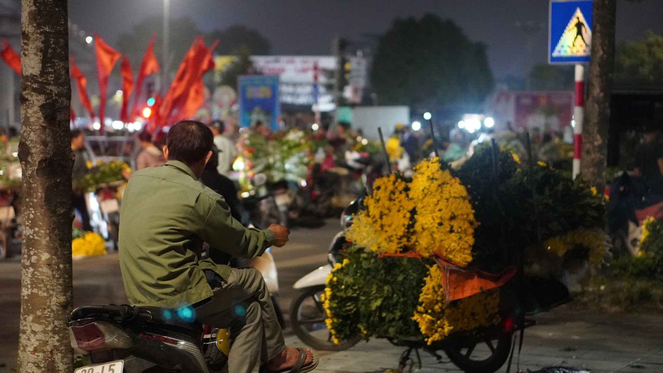 Anh Phương lặng lẽ nhìn dòng người chọn những cành hoa ưng ý để bán lễ Rằm tháng Giêng. Ảnh: Minh Vũ 