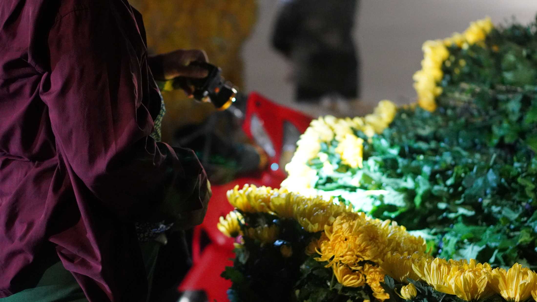 Đèn pin trở thành “trợ thủ” không thể thiếu của tiểu thương trong những phiên chợ hoa xuyên đêm. Ảnh: Minh Vũ 