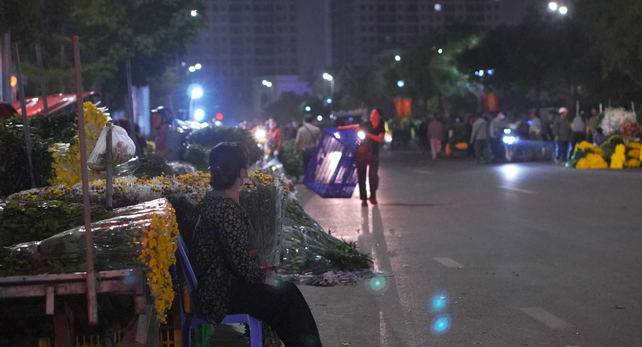 Người bán ngồi bên những bó hoa tươi, hy vọng một đêm buôn may bán đắt. Ảnh: Minh Vũ 