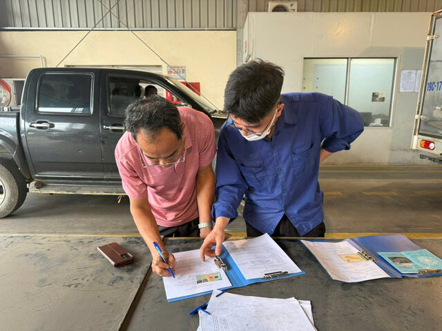 Đăng kiểm viên giải thích để chủ xe làm bản cam kết tự nguyện kiểm tra khí thải. Ảnh: Minh Nguyễn