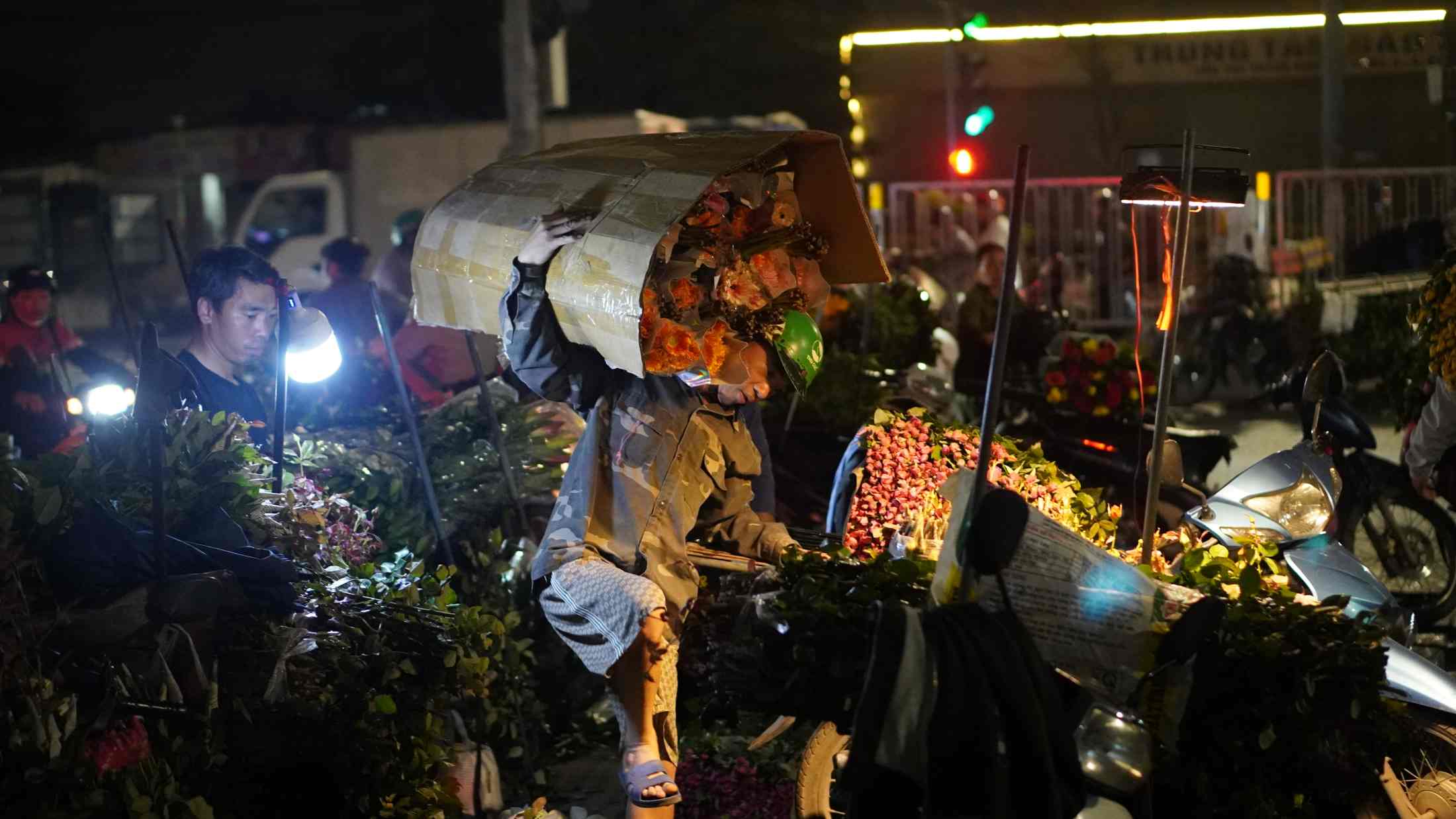 Tiểu thương tất bật bốc dỡ hoa từ xe tải, chuẩn bị cho một phiên chợ xuyên đêm. Ảnh: Minh Vũ