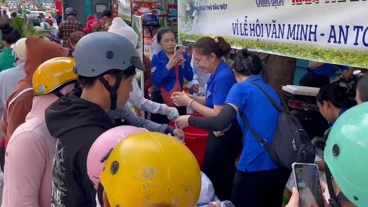 People are allowed to take motorbike taxis and receive free drinking water at the full moon festival in Thu Dau Mot ward, Ho Chi Minh City. Photo: Dinh Trong