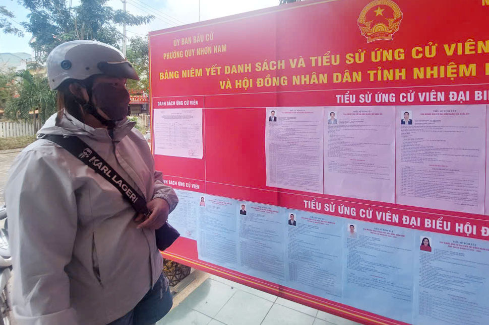 La gente ve la lista de candidatos a diputados de la Asamblea Nacional XVI y diputados del Consejo Popular Provincial de Gia Lai para el mandato 2026-2031 publicada en el barrio de Quy Nhon Nam. Foto: Hoai Phuong