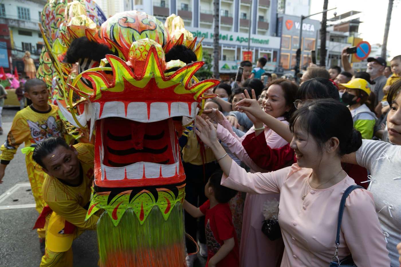 Nhiều người dân tranh thủ chạm tay vào lân, rồng và các nhân vật hóa trang để cầu mong năm mới bình an, tài lộc. Ảnh: Thái Bảo.