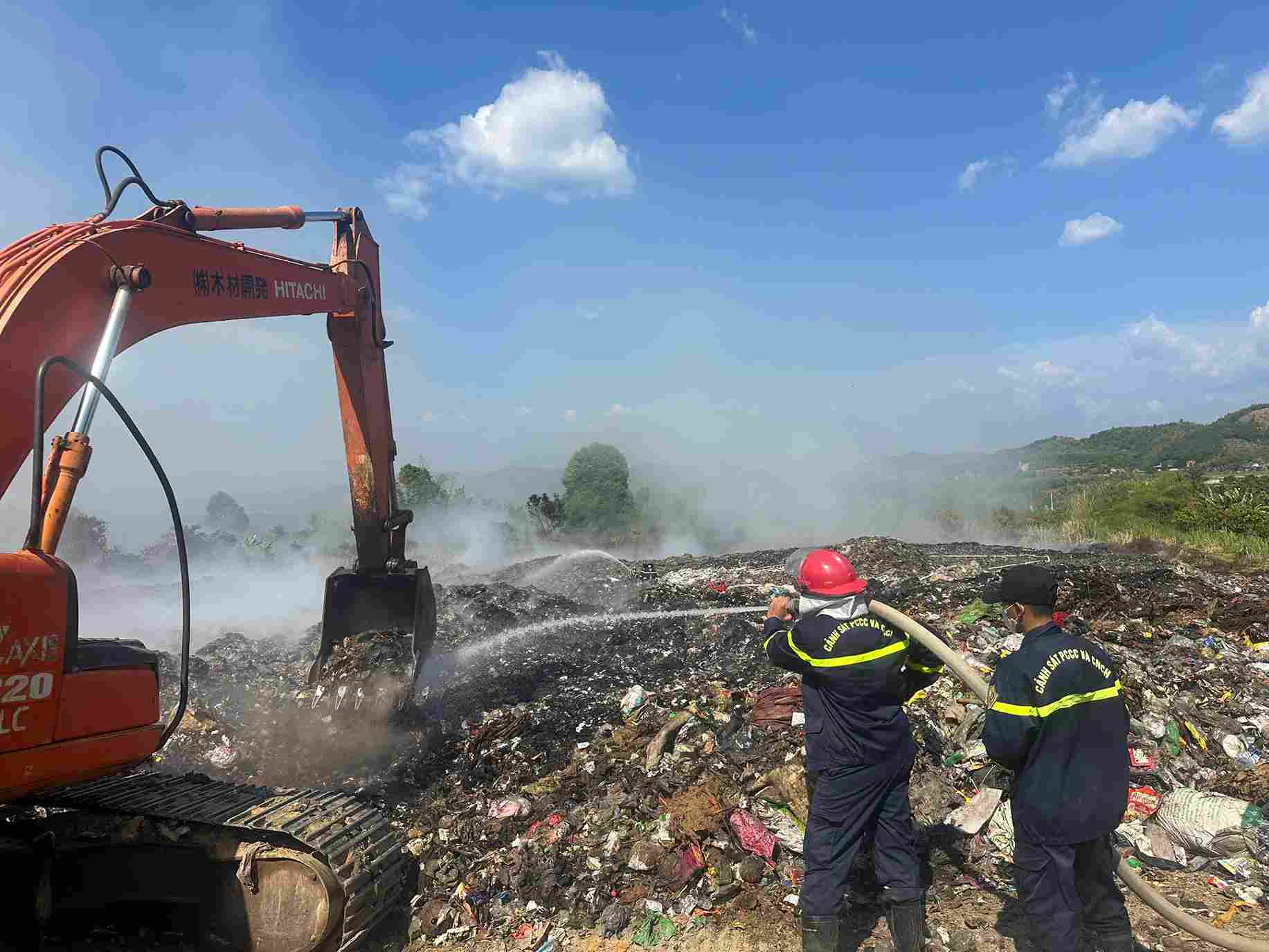Cùng với phun nước dập lửa, lực lượng chức năng sử dụng máy múc đảo rác chống cháy lan. Ảnh: Phúc Khánh
