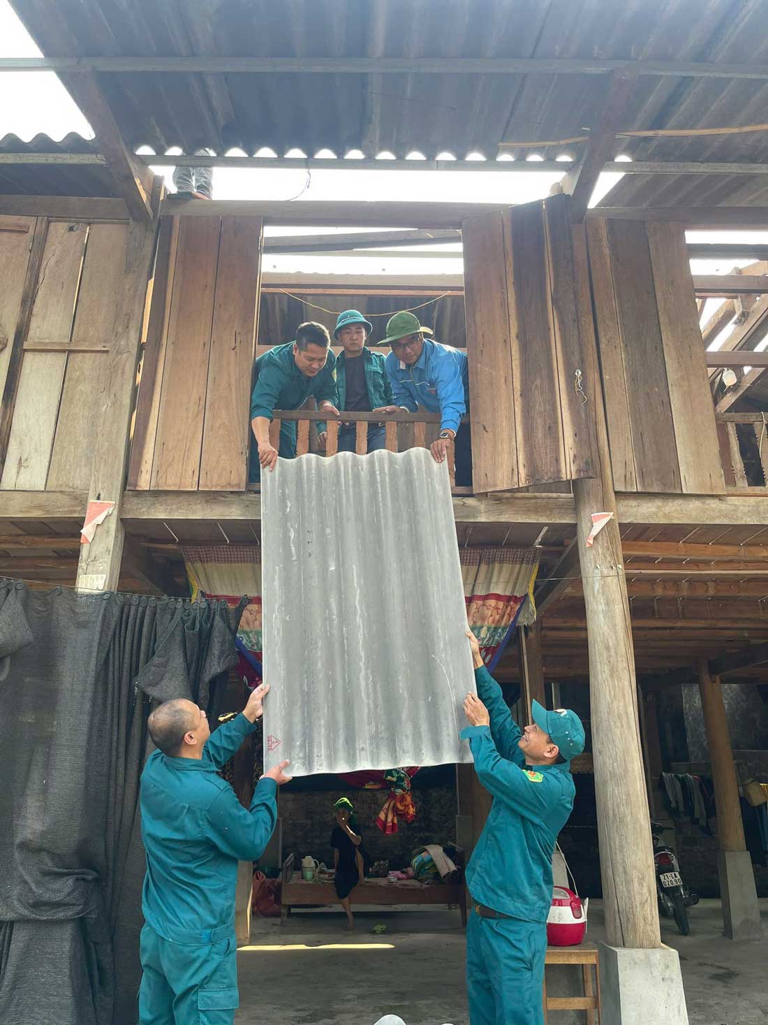 Lực lượng đoàn viên, dân quân phối hợp vận chuyển tấm lợp, khắc phục thiệt hại nhà ở.