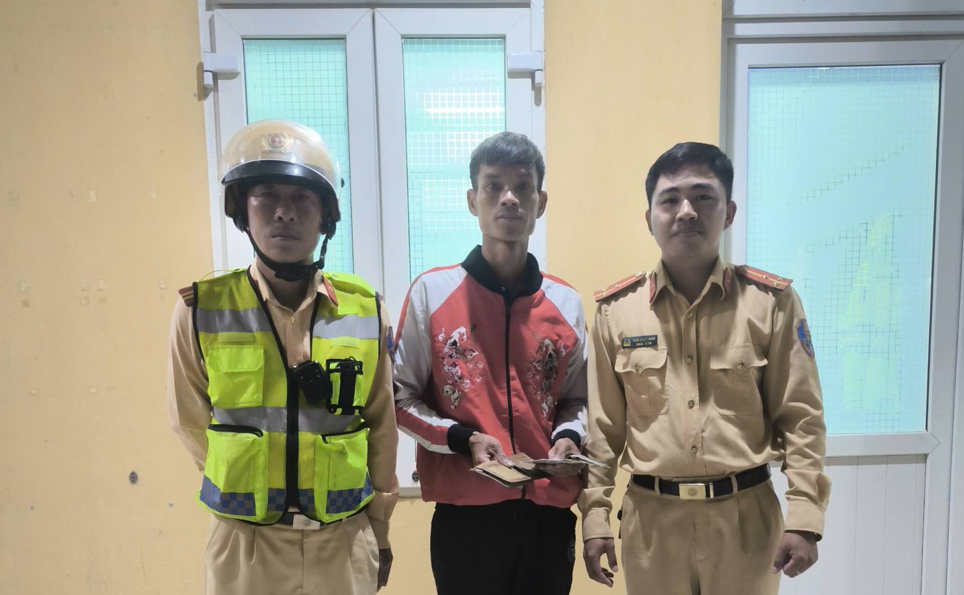 교통 경찰이 분실자에게 재산을 돌려주고 있습니다. 사진: H. Nhung.