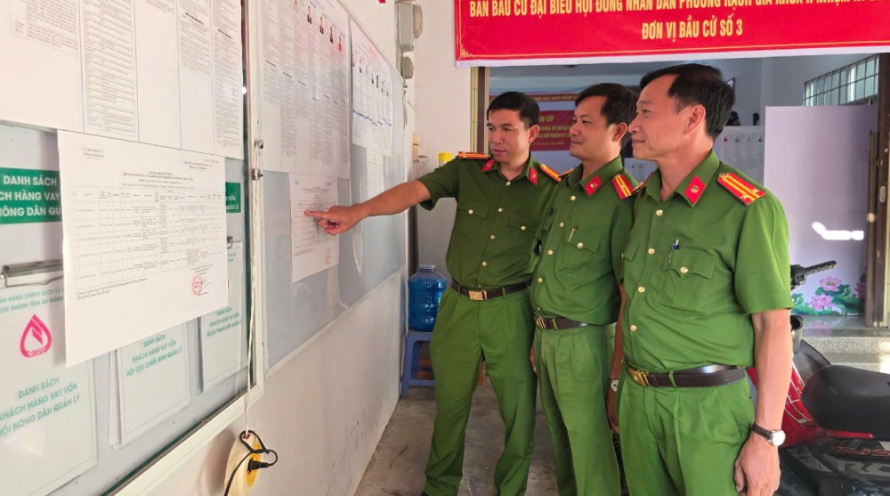 Công an phường Rạch Giá kiểm tra danh sách đại biểu ứng cử tại các điểm bỏ phiếu. Ảnh: Văn Vũ