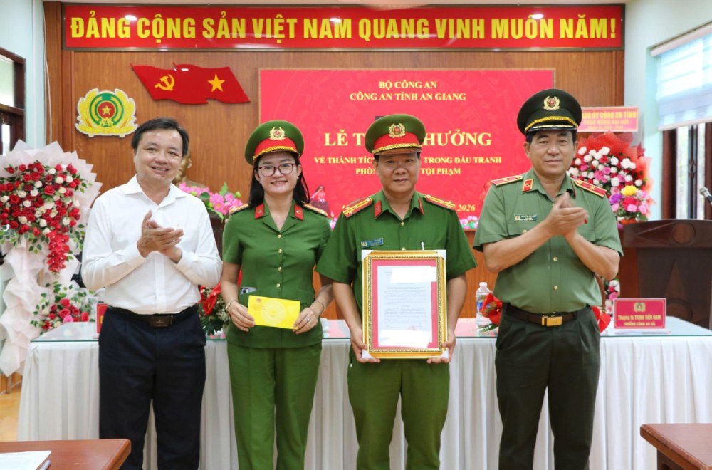 Thiếu tướng Nguyễn Văn Hận, Giám đốc Công an tỉnh An Giang và ông Dương Minh Tâm (áo trắng), Bí thư Đảng ủy xã Hòn Đất trao quyết định và tiền thưởng cho Công an xã Hòn Đất. Ảnh: Tiến Dũng
