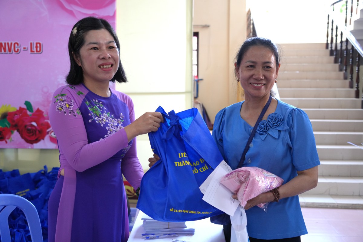 Một lao động nữ nhận phần quà của tổ chức Công đoàn sau khi được tư vấn, khám bệnh miễn phí; nhận chiếc áo dài ưng ý. Ảnh: Thành An
