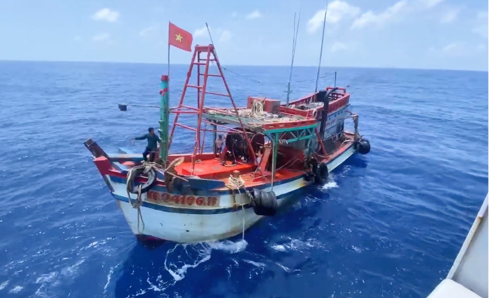 Coast guard ship approaches fishing boat to rescue fishermen.