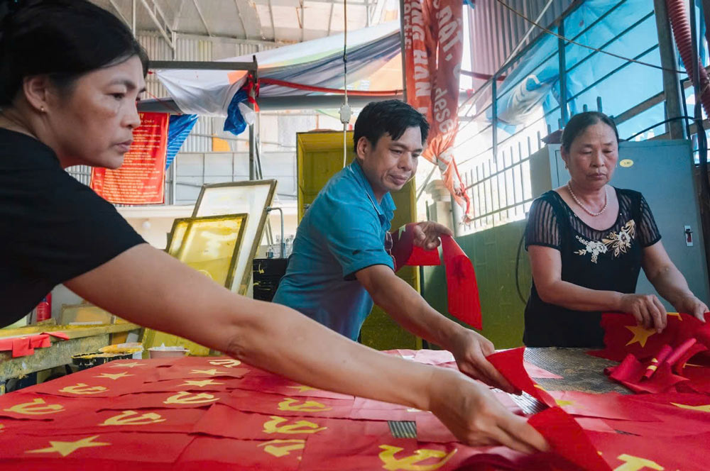 Anh Phục tất bật làm việc để kịp cung ứng cờ cho thị trường toàn quốc. Ảnh: Thanh Hằng