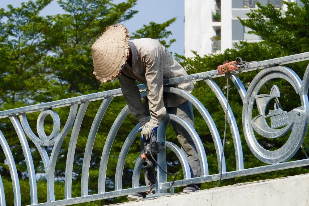 Công nhân khẩn trương lắp đặt hệ thống lan can an toàn trên nhánh cầu vượt N3 thuộc nút giao An Phú. Ảnh: Thái Bảo