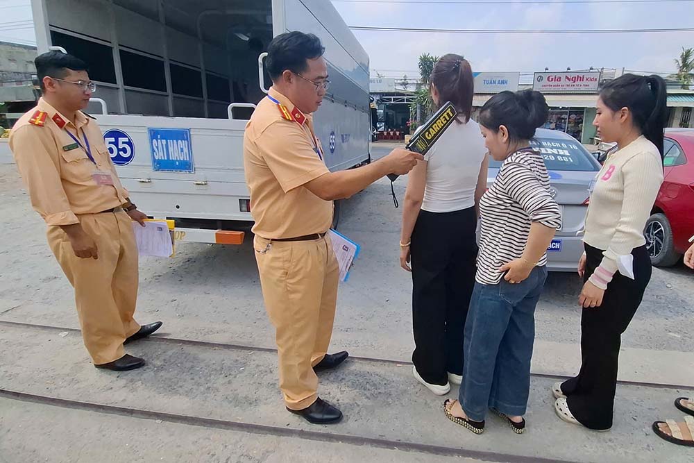 Test takers use specialized equipment to scan and detect electronic means of fraud in the theoretical driving test. Photo: Thanh Vu