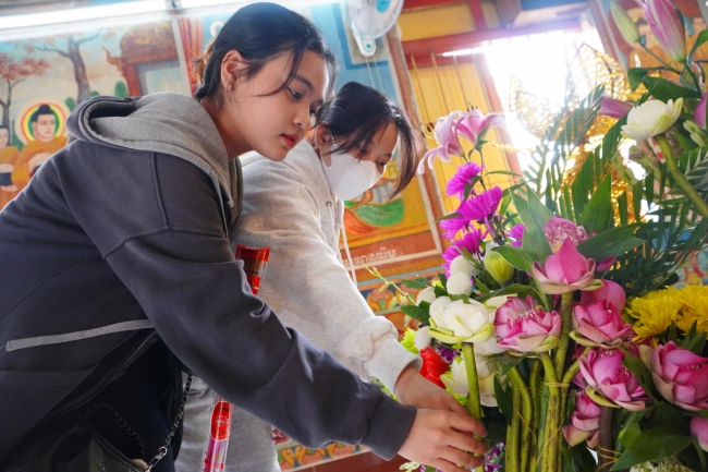 Các bạn trẻ thành kính dâng hoa lễ Phật. 