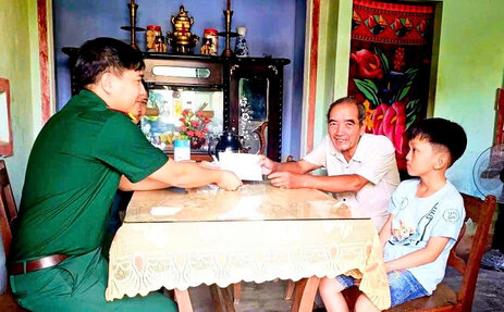 Thiếu tá Huỳnh Hữu Trí, Chính trị viên phó Ban Chỉ huy quân sự xã Long Phụng thăm hỏi, động viên gia đình em Nguyễn Ngọc Phát học lớp 3A, Trường Tiểu học Đức Hiệp, Thôn Nghĩa Lập, xã Long Phụng. Ảnh: Trọng Quốc