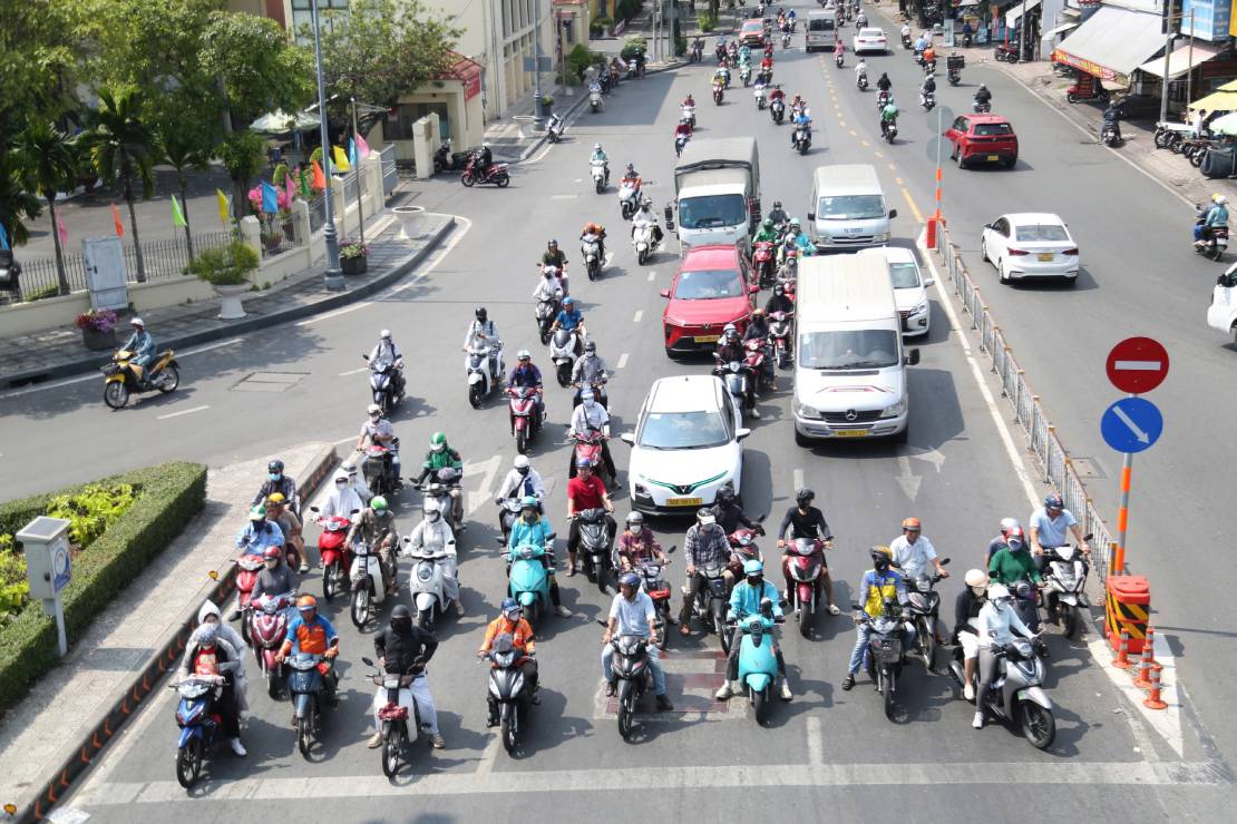 Người đi xe máy trùm kín áo mũ, lưu thông trên một tuyến đường thiếu bóng mát giữa trưa. Ảnh: Mai Anh.