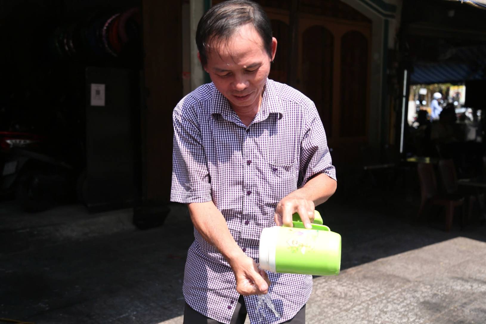 Trời quá nắng nóng, người đàn ông này phải thường xuyên rửa tay, mặt để giảm nhiệt. Ảnh: Mai Anh. 