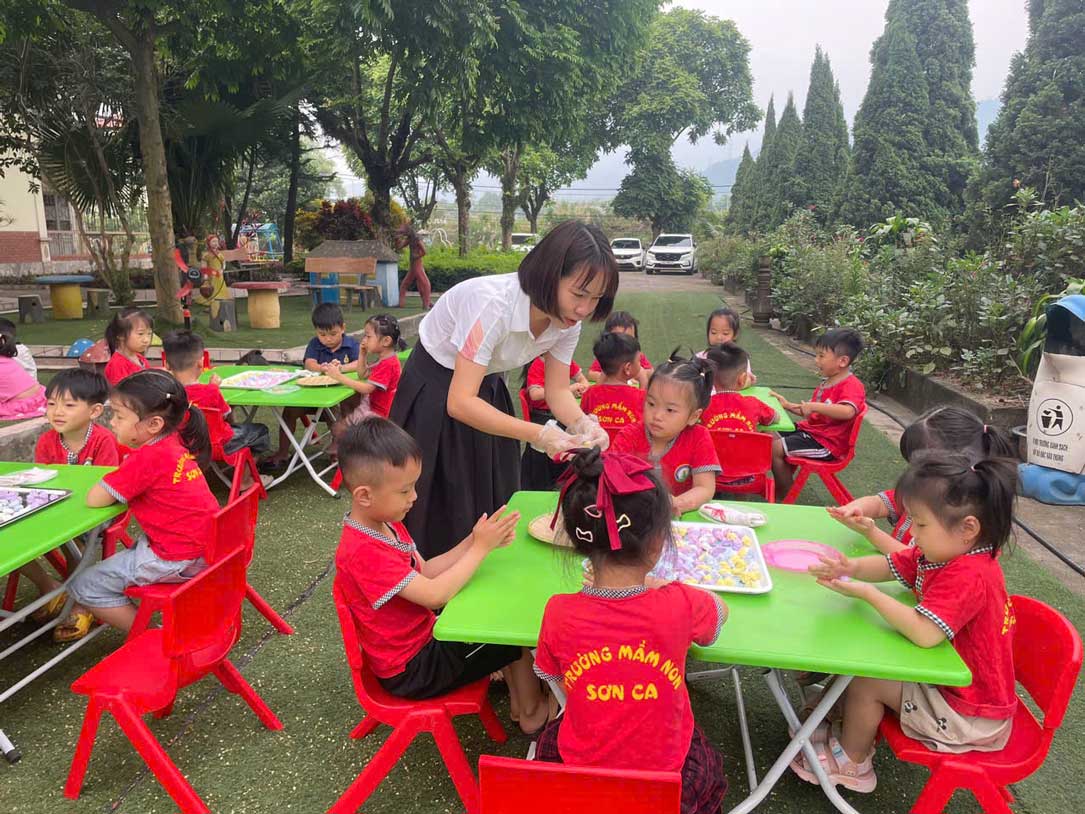 Trẻ mầm non hào hứng tham gia hoạt động nặn bánh trôi ngoài trời.