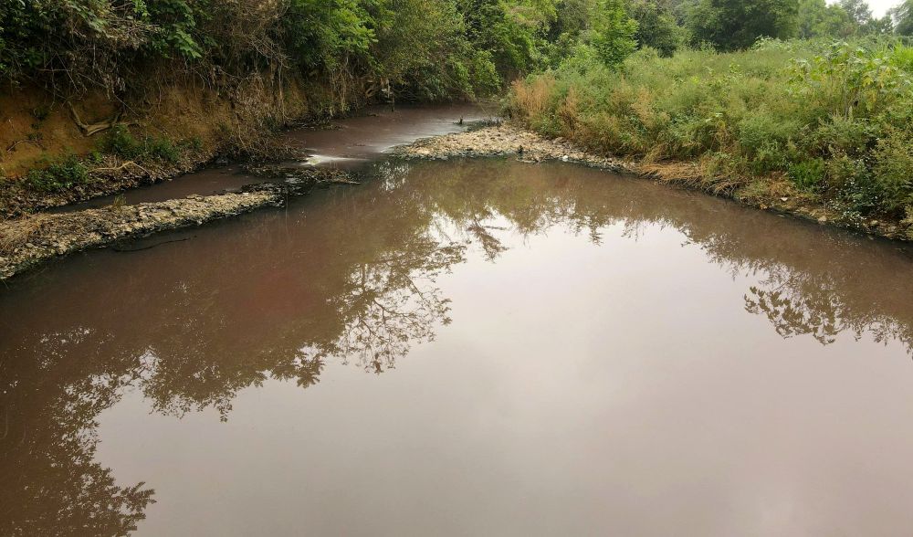 Không chỉ nước giếng khoan, tại khu vực suối Bãi Rơn nguồn nước cũng chuyển màu và bốc mùi hôi tanh. Ảnh: Quách Du