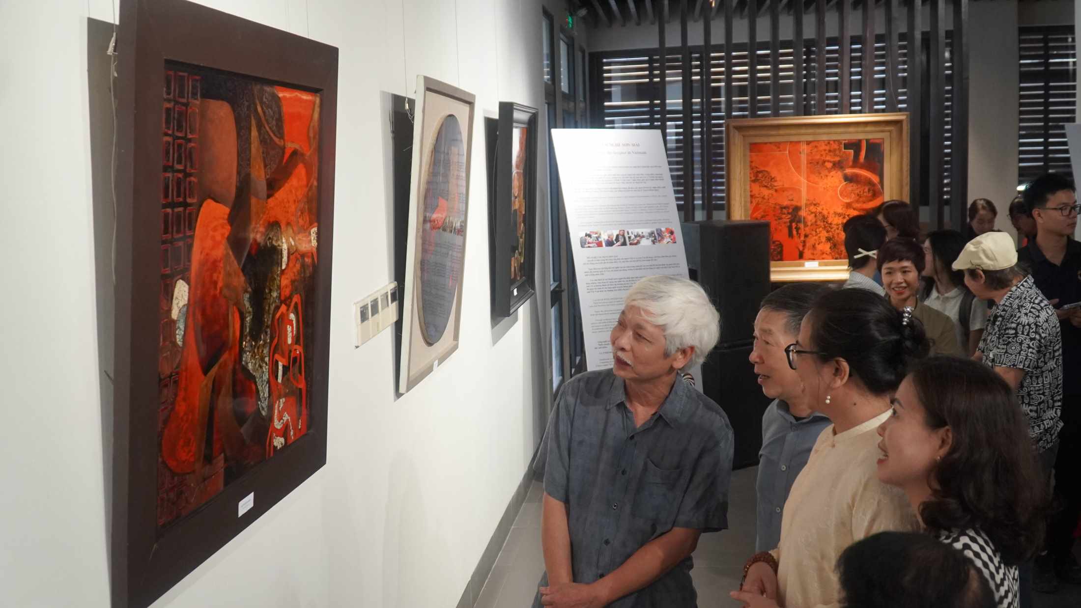 Artist Nguyen Dinh Bang shares the story of lacquer paintings with visitors to the exhibition. Photo: Minh Vu