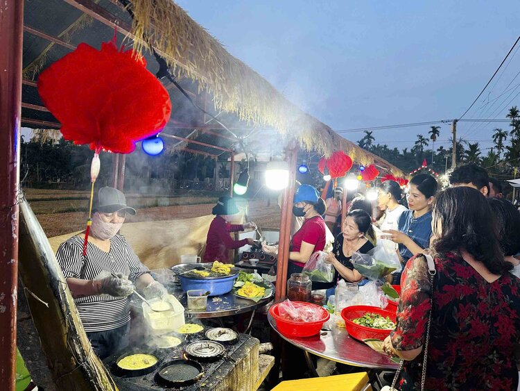 Du khách thưởng thức món bánh xèo được chế biến ngay trên cánh đồng ở làng du lịch cộng đồng tại thôn Bình Thành. Ảnh: Xuân Hoanh