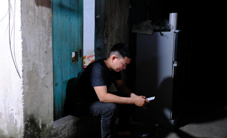 Returning to his rented room after a hard working day, Mr. Tuan sat resting outside to reduce the stuffiness. Photo: My Ly