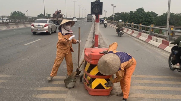 Công hân Công ty CP Công trình giao thông Hà Nội vệ sinh biển báo trên cầu Thanh trì. Ảnh: Quang Bảo